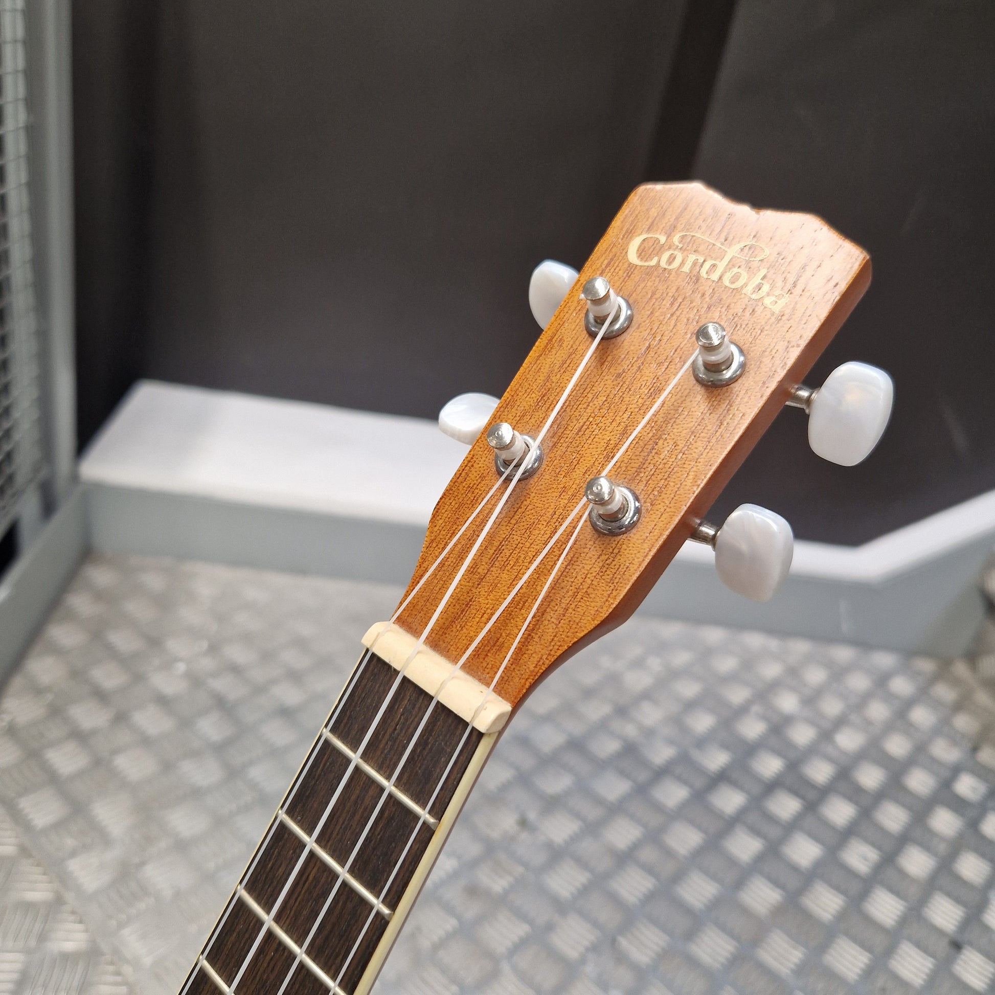 Pre-Owned Cordoba 15CM Close-up of a guitar headstock with 'Cordoba' branding on a blurred background