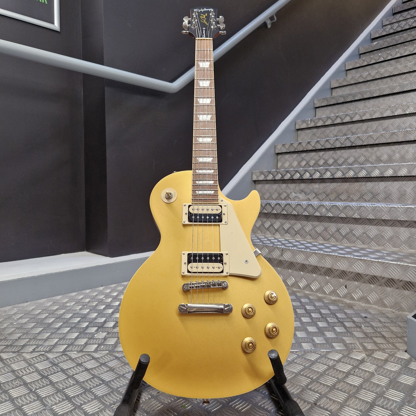 Pre-Owned Epiphone Les Paul yellow electric guitar on a stand with stairs in the background