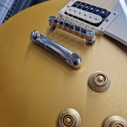 Pre-Owned Epiphone Les Paul Close-up of a gold electric guitar with control knobs and bridge.