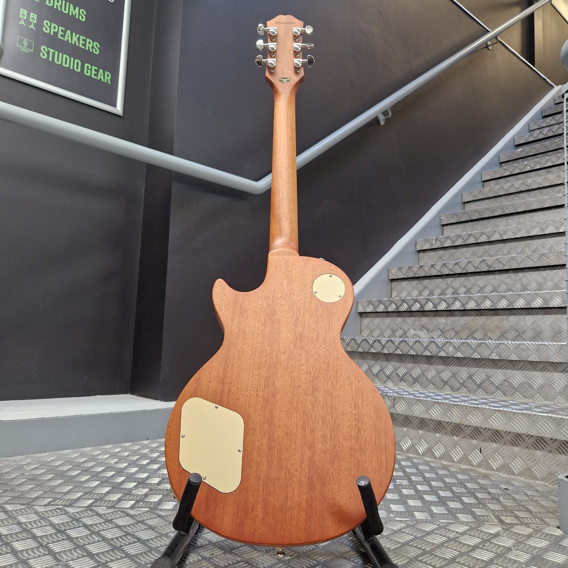Pre-Owned Epiphone Les Paul Wooden guitar on a stand in front of a staircase with 'Studio Gear' sign.
