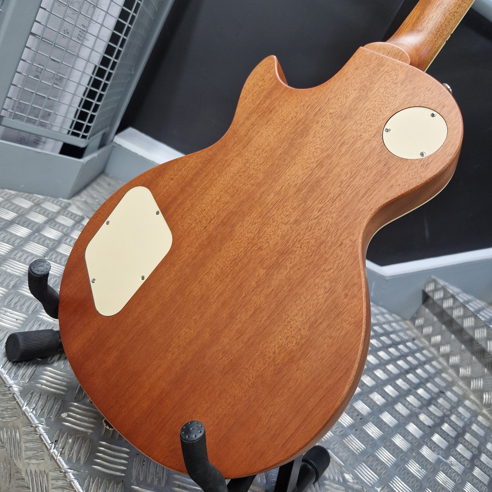 Pre-Owned Epiphone Les Paul Wooden electric guitar body on a stand with a metallic floor background