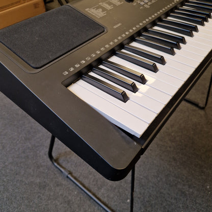 Pre-Owned Yamaha PSR-EW310 Close-up of a keyboard with a stand on a tiled floor