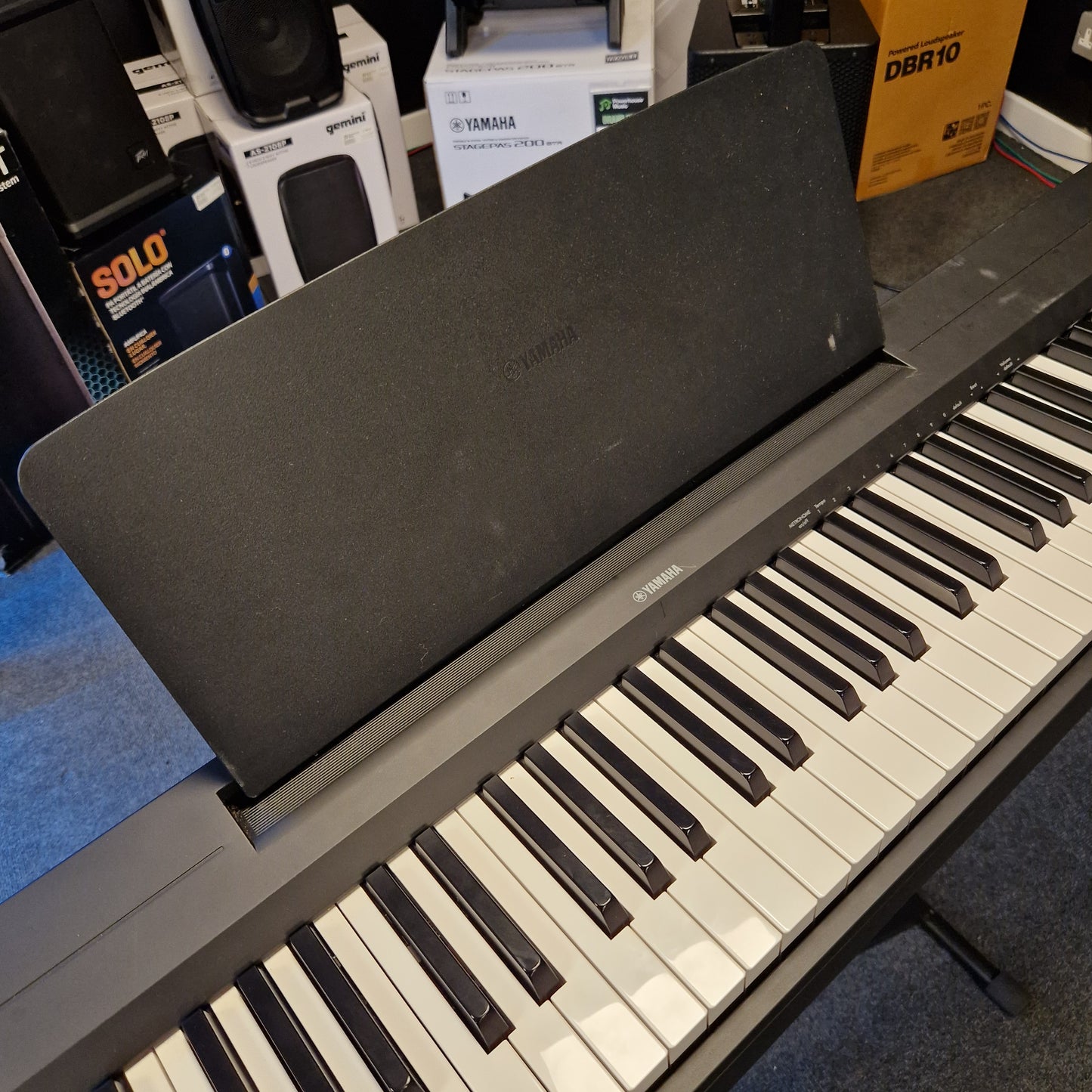 Pre-Owned Yamaha P-145B Digital piano with a black stand in a room setting