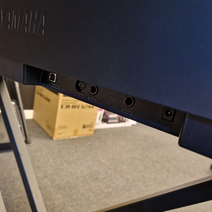 Pre-Owned Yamaha P-145B Back view of a blue electronic device with ports on a reflective surface.