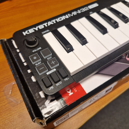 Pre-Owned M-Audio Keystation Mini 32 Mini keyboard with control panel on a wooden surface