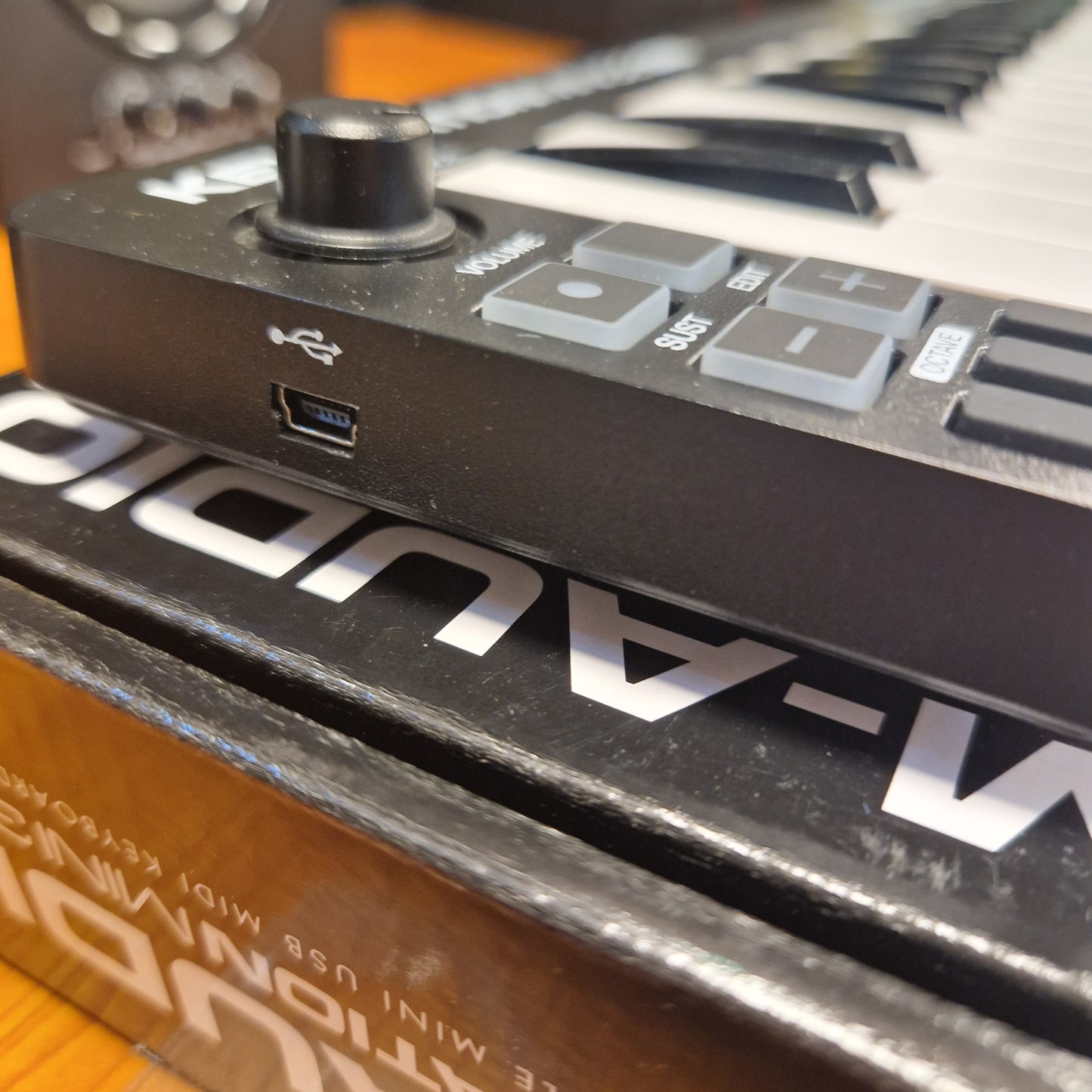 Pre-Owned M-Audio Keystation Mini 32 Close-up of a M-Audio electronic device with USB and MIDI ports.