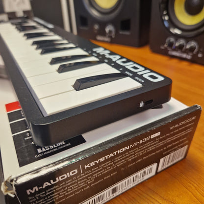 Pre-Owned M-Audio Keystation Mini 32 M-Audio keyboard with packaging on a wooden surface
