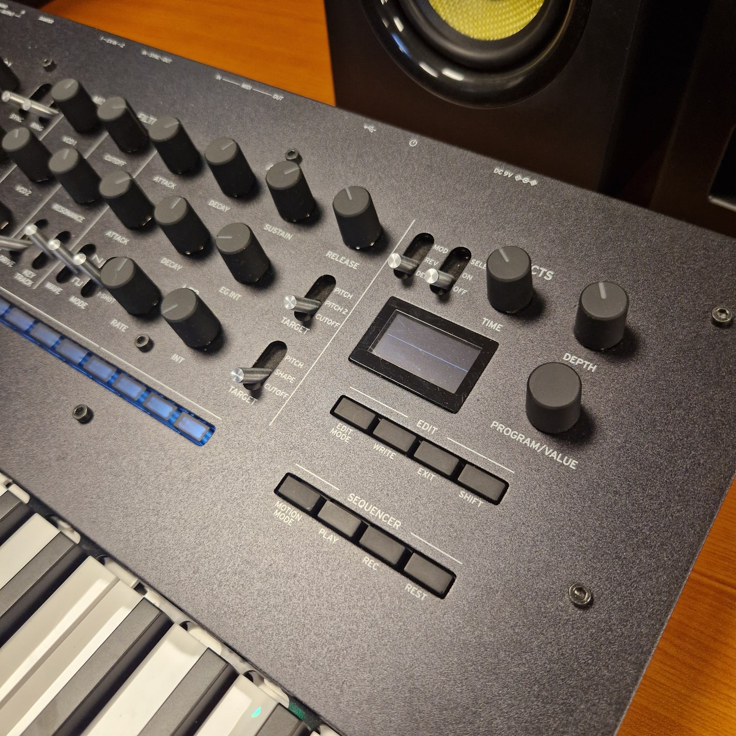 Pre-Owned Korg Minilogue XD Close-up of a music production controller with knobs and buttons on a wooden surface.