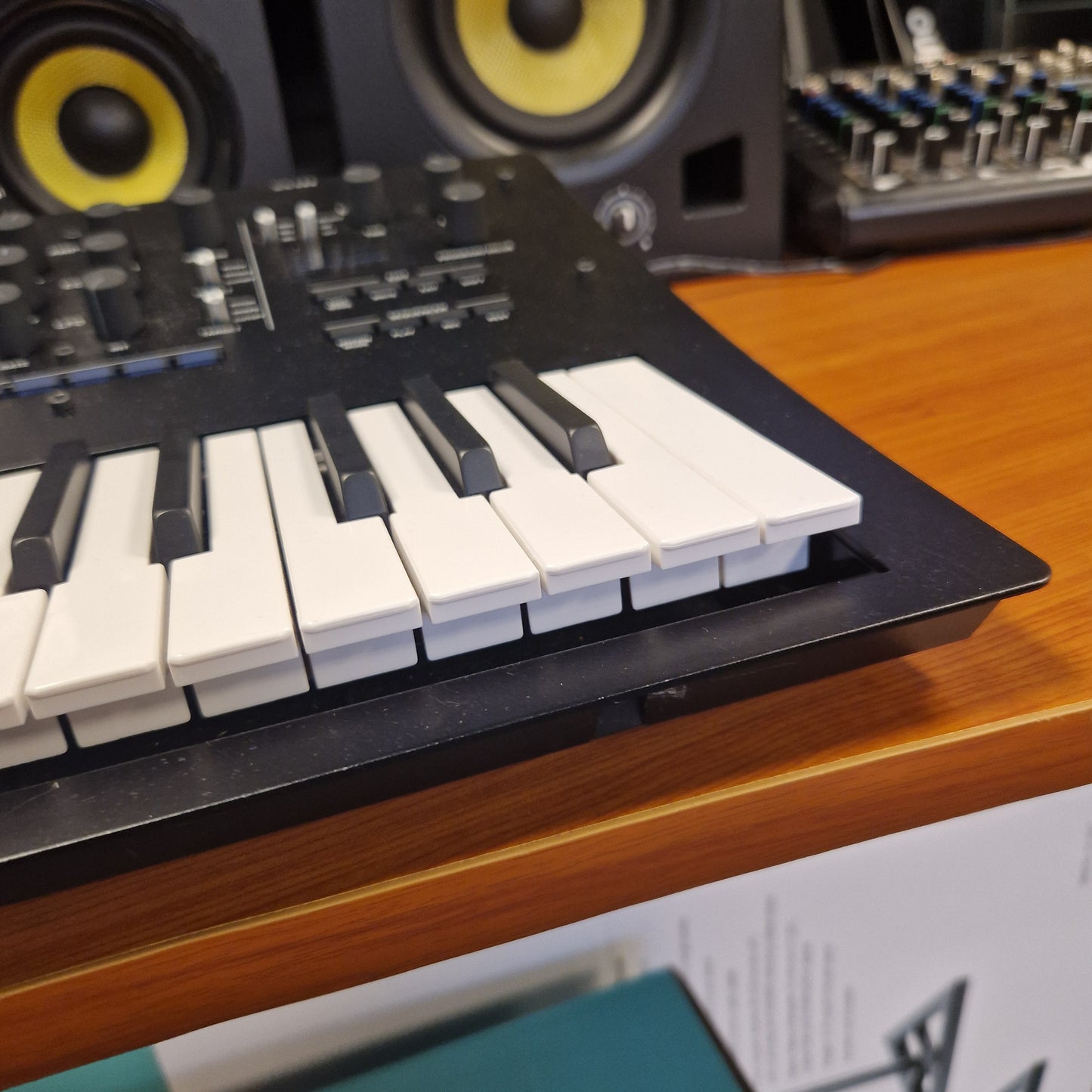 Pre-Owned Korg Minilogue XD Keyboard controller on a wooden surface with audio equipment in the background
