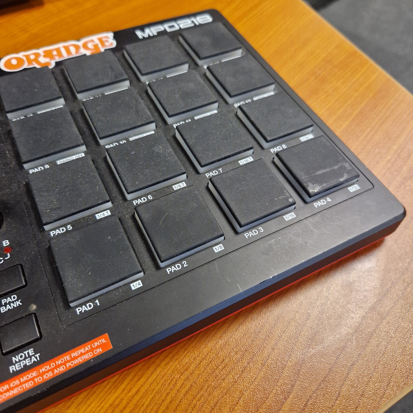 Pre-Owned Akai MPD218 Orange electronic keyboard or controller on a wooden surface