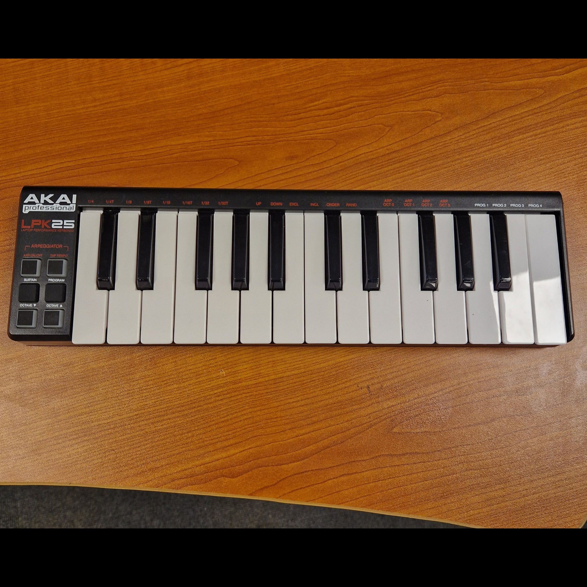 Pre-Owned Akai LPK25 Mini keyboard on a wooden surface