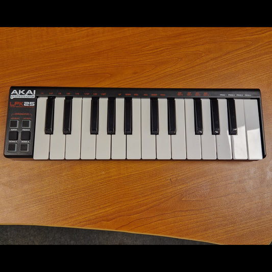 Pre-Owned Akai LPK25 Mini keyboard on a wooden surface