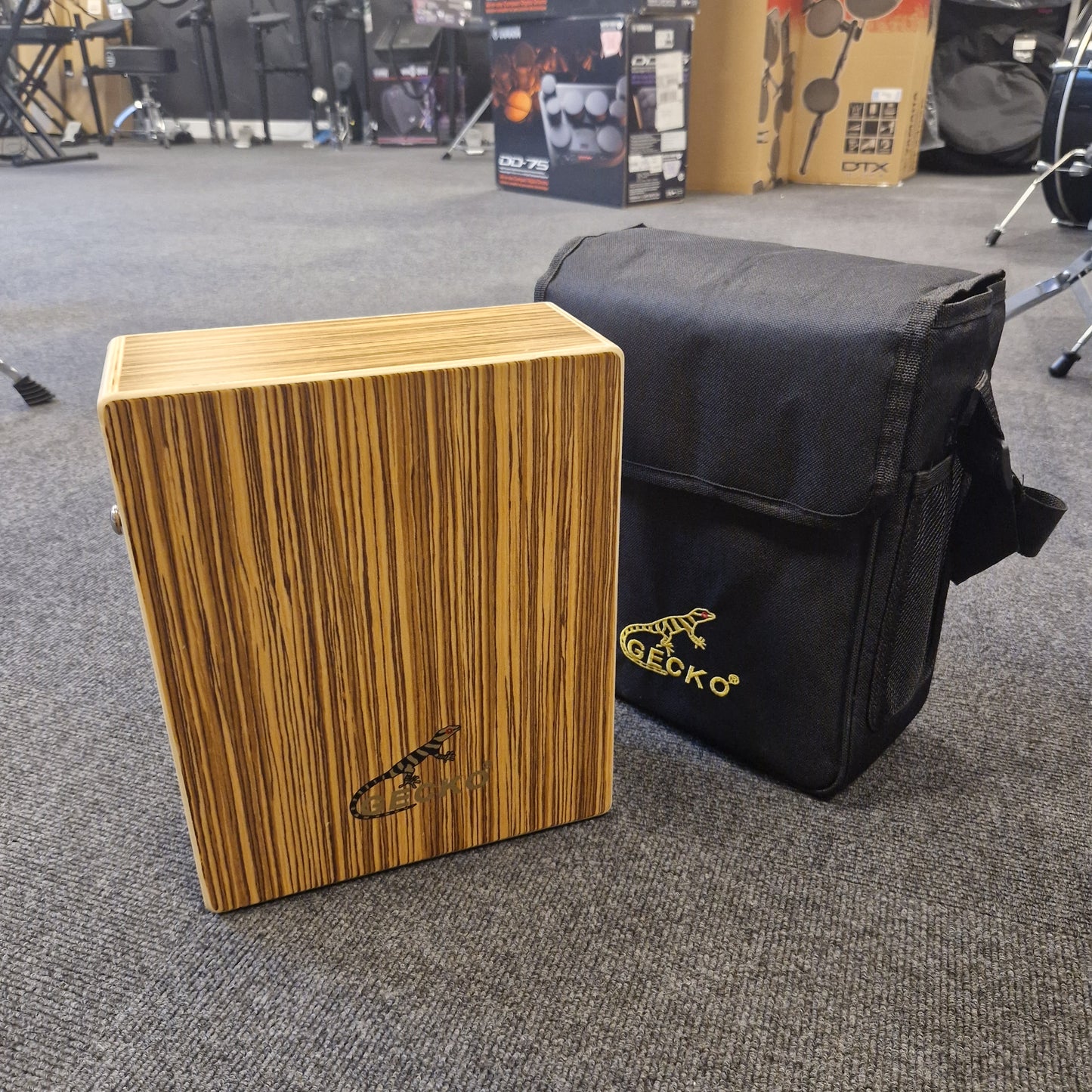 Pre-Owned Gecko C-68Z Wooden cajon drum with a black carrying bag on a gray floor
