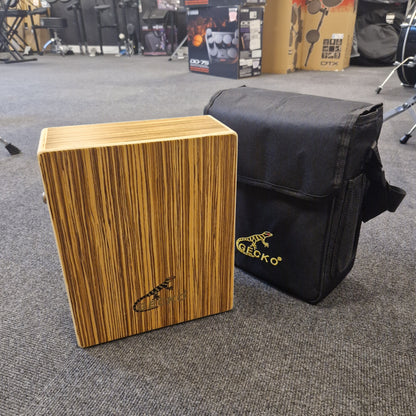 Pre-Owned Gecko C-68Z Wooden cajon drum with a black carrying bag on a gray floor
