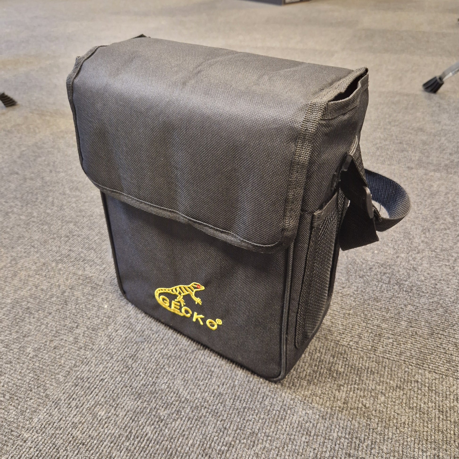 Pre-Owned Gecko C-68Z Black bag with a yellow logo on a gray carpet