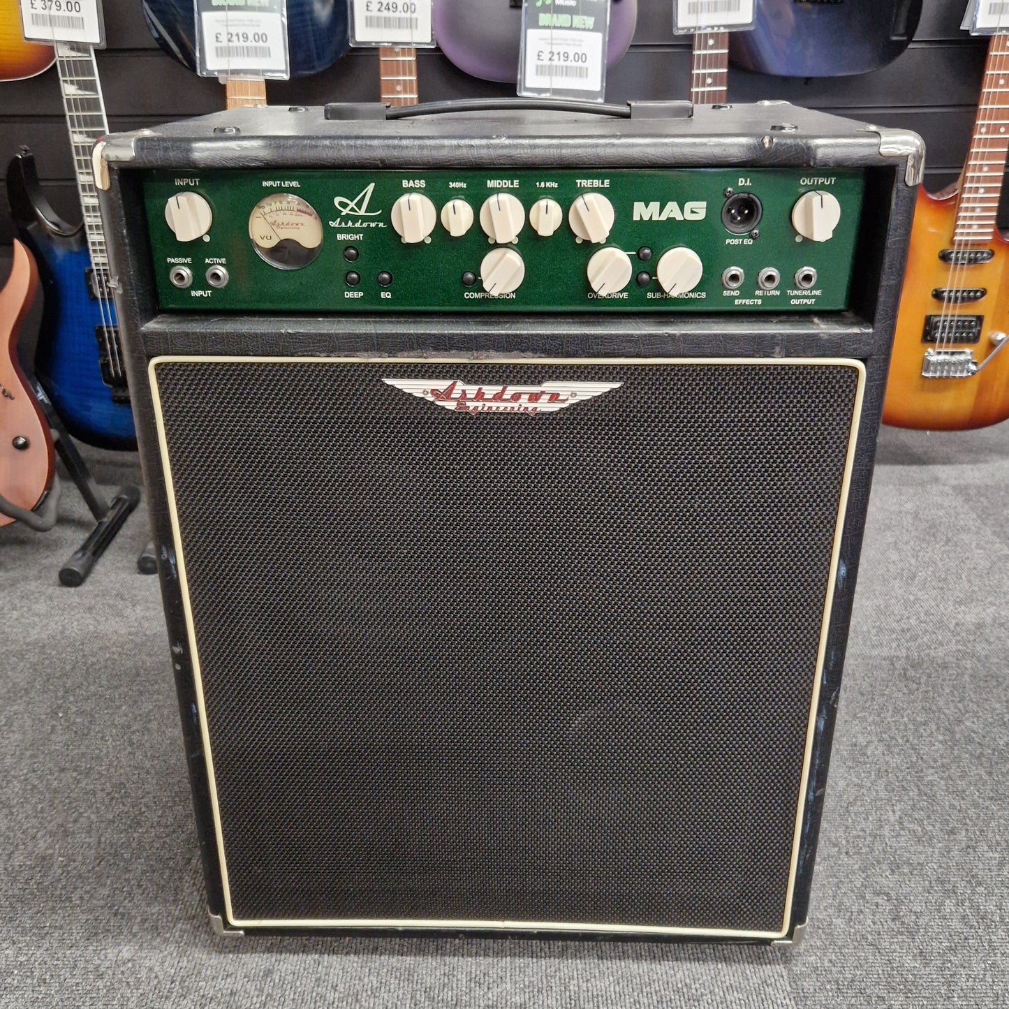 Pre-Owned Ashdown MAG-C210T-300EVO Guitar amplifier and speaker on a gray floor with guitars in the background 