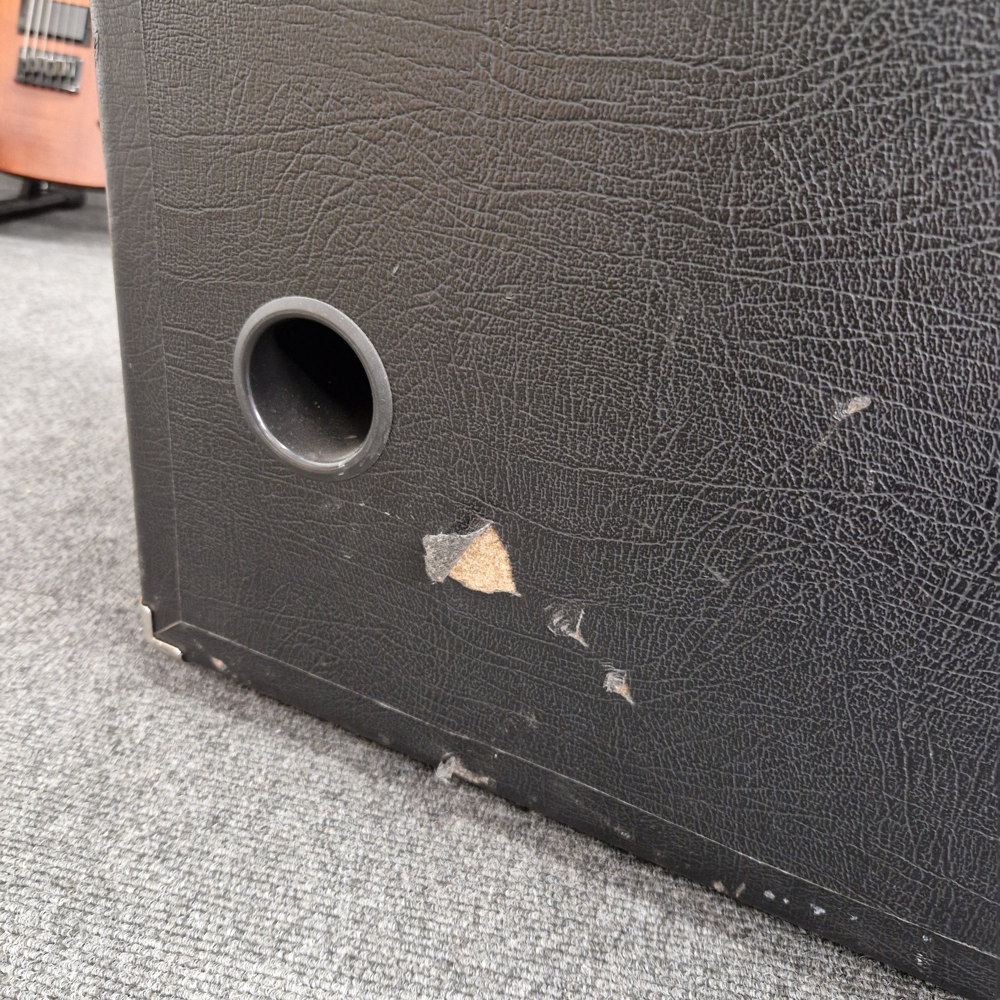 Pre-Owned Ashdown MAG-C210T-300EVO Close-up of a textured black surface with a circular hole, possibly a speaker or electronic component.