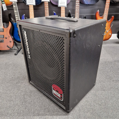 Pre-Owned TC Electronic BG250-112 Black speaker with a brand logo on a gray floor, surrounded by guitars