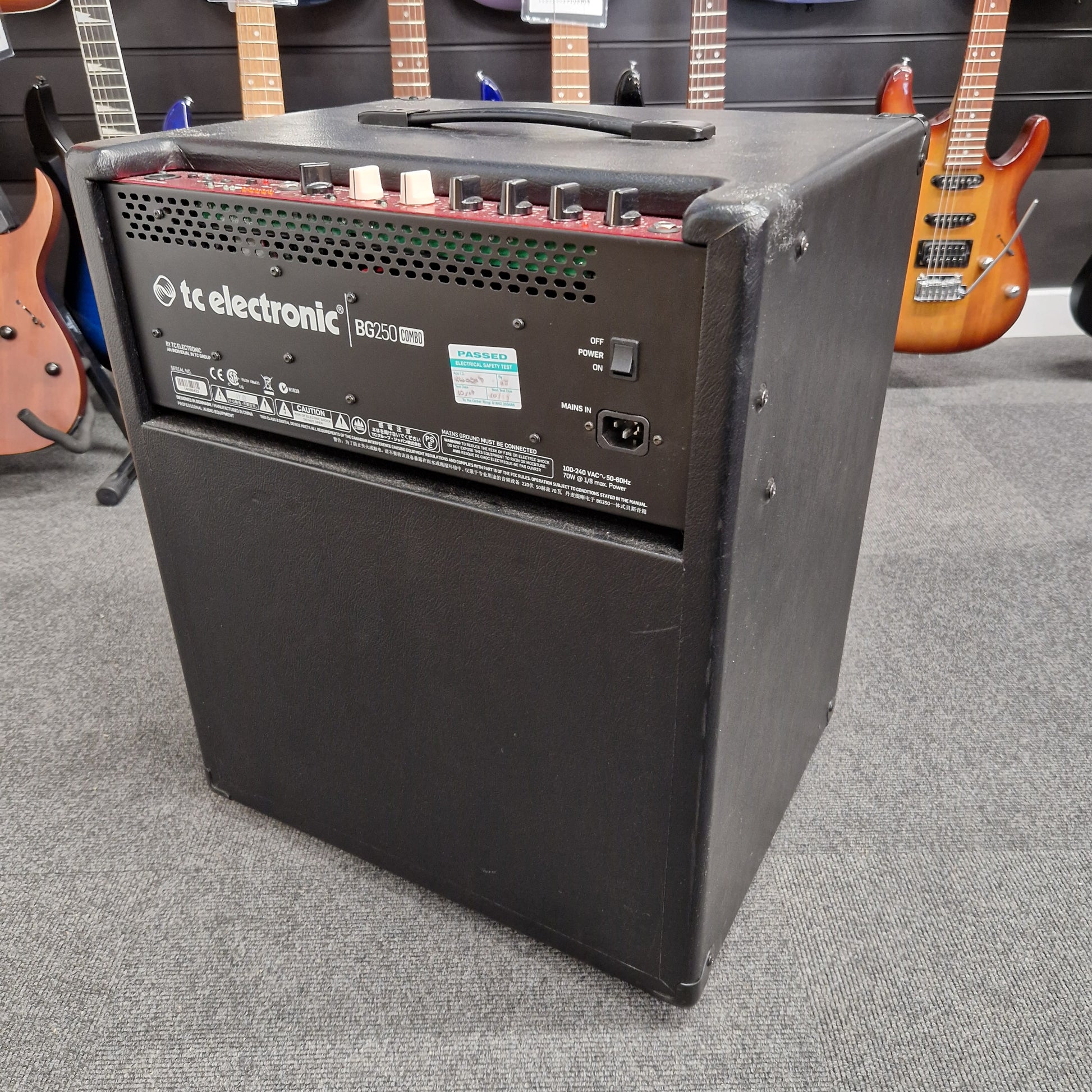 Pre-Owned TC Electronic BG250-112 Black electronic device with 'kc electronic' branding on a gray surface with guitars in the background