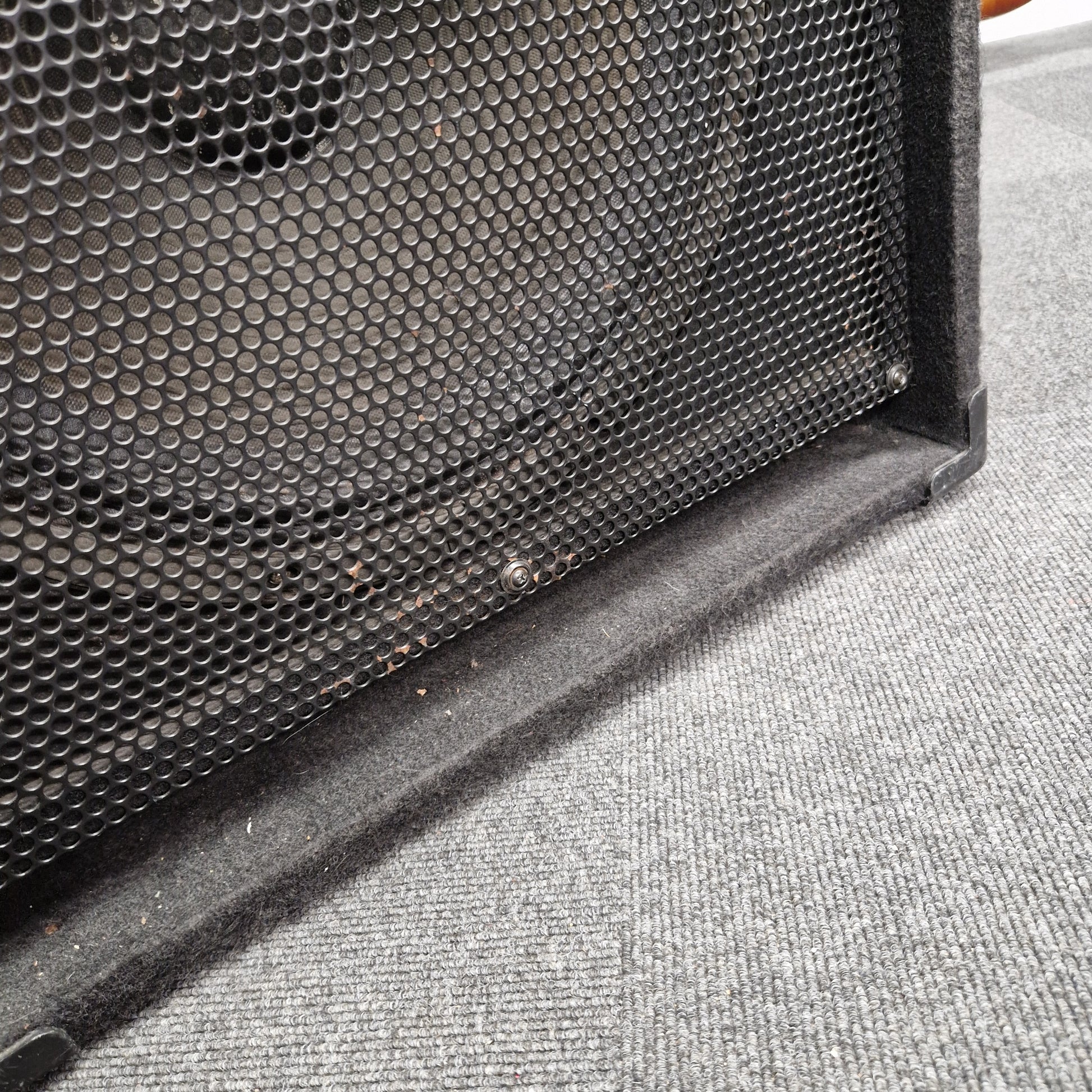 Pre-Owned Fender Rumble 100 Black speaker grill on a textured gray surface