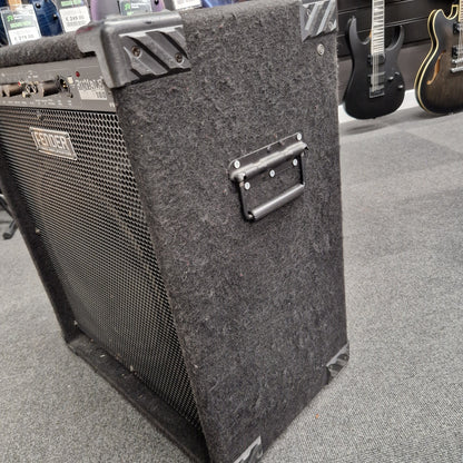 Pre-Owned Fender Rumble 100 Guitar amplifier on a gray floor with guitars in the background