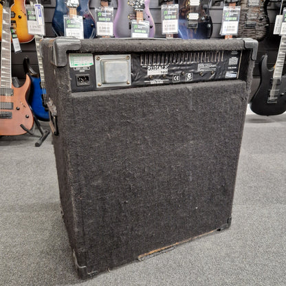 Pre-Owned Fender Rumble 100 Guitar amplifier on a gray floor with guitars in the background