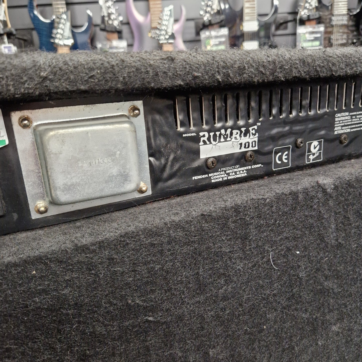 Pre-Owned Fender Rumble 100 Guitar amplifier with 'Rumble 100' branding in a store setting