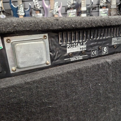 Pre-Owned Fender Rumble 100 Guitar amplifier with 'Rumble 100' branding in a store setting