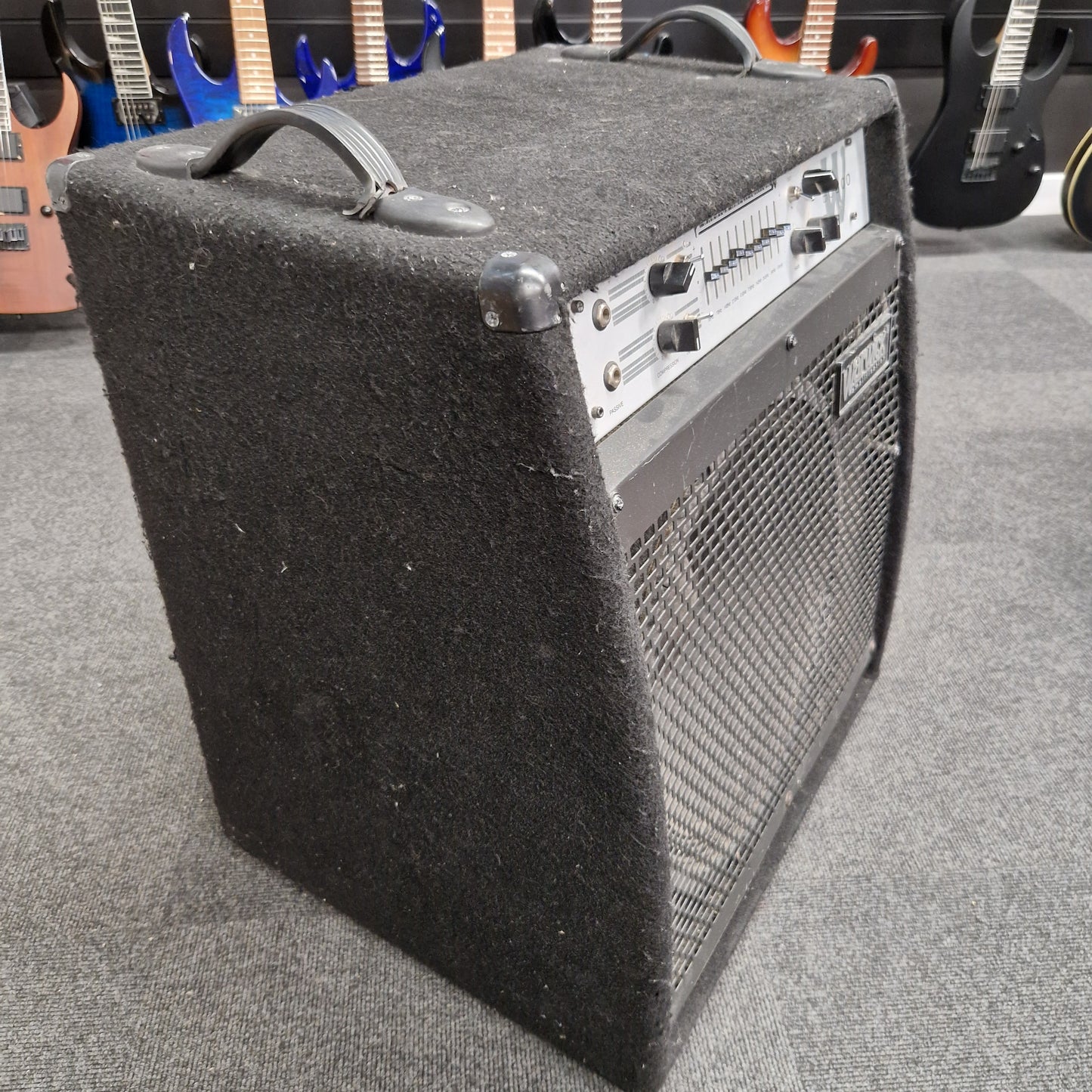 Pre-Owned Warwick BC300 Guitar amplifier on a gray surface with guitars in the background