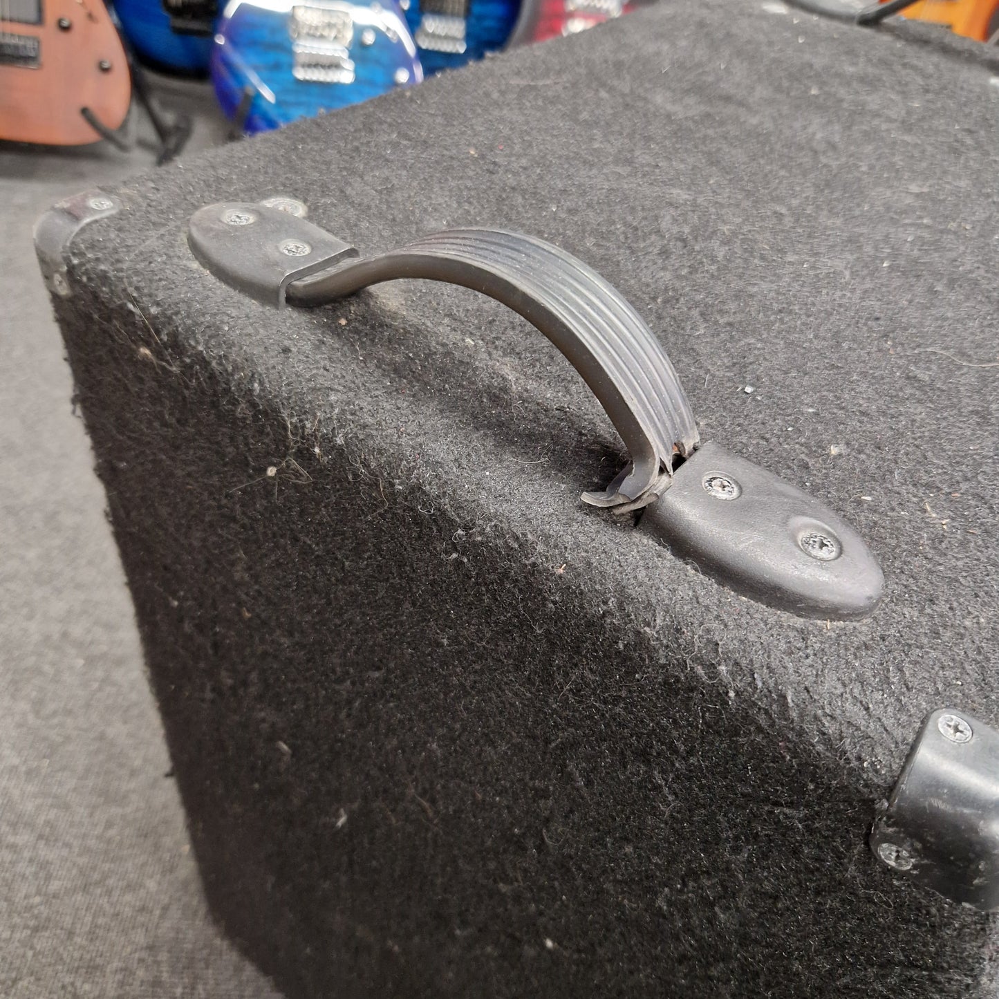 Pre-Owned Warwick BC300 Close-up of a guitar case handle on a black guitar case with a blurred background.