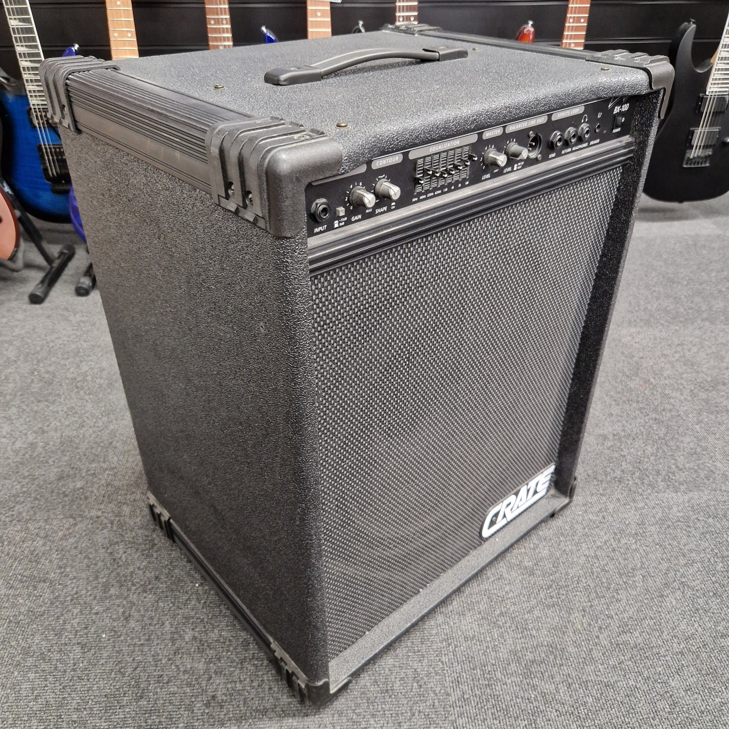 Pre-Owned Crate BX-100 Guitar amplifier on a gray carpet with guitars in the background