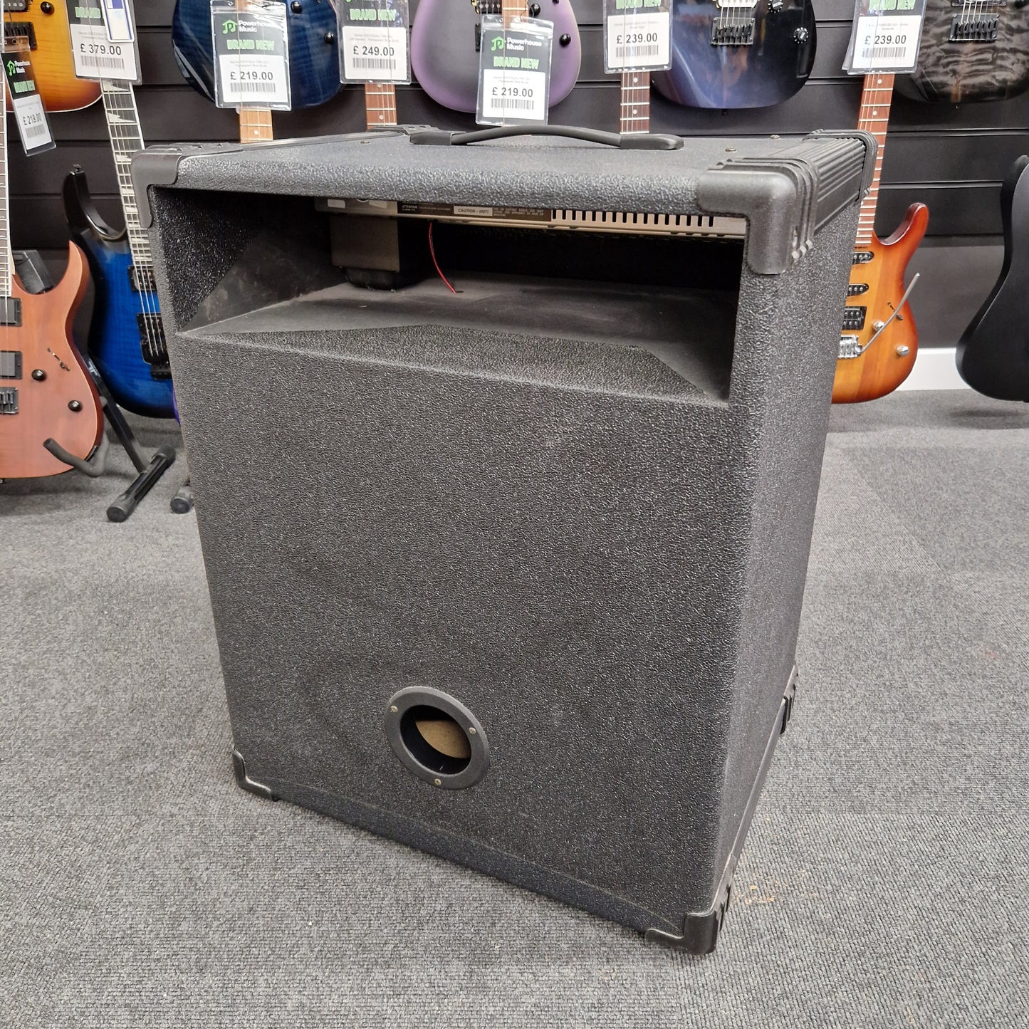 Pre-Owned Crate BX-100 Gray speaker cabinet on a gray floor with guitars in the background