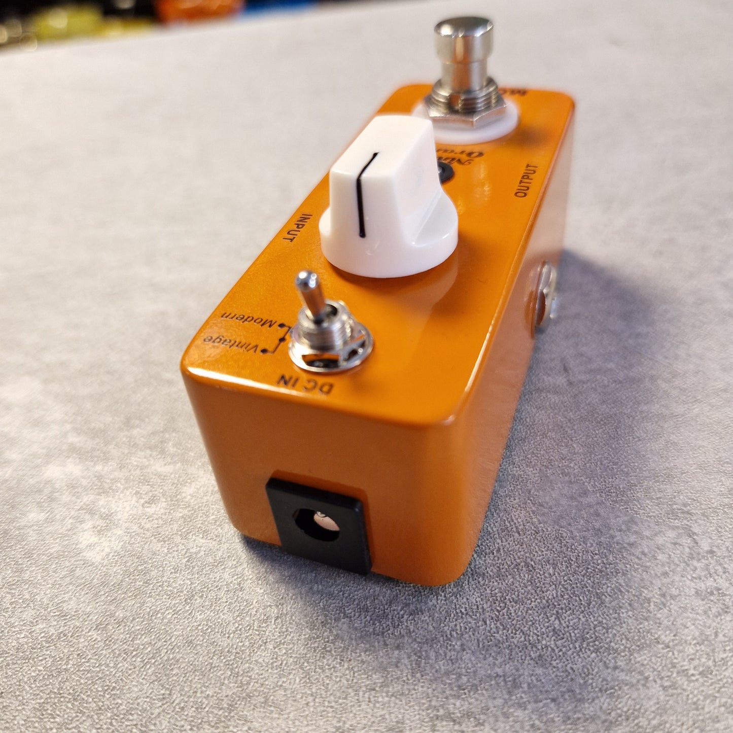 Pre-Owned Mooer MPH1 Orange guitar effects pedal with white knob and black switch on a textured gray background