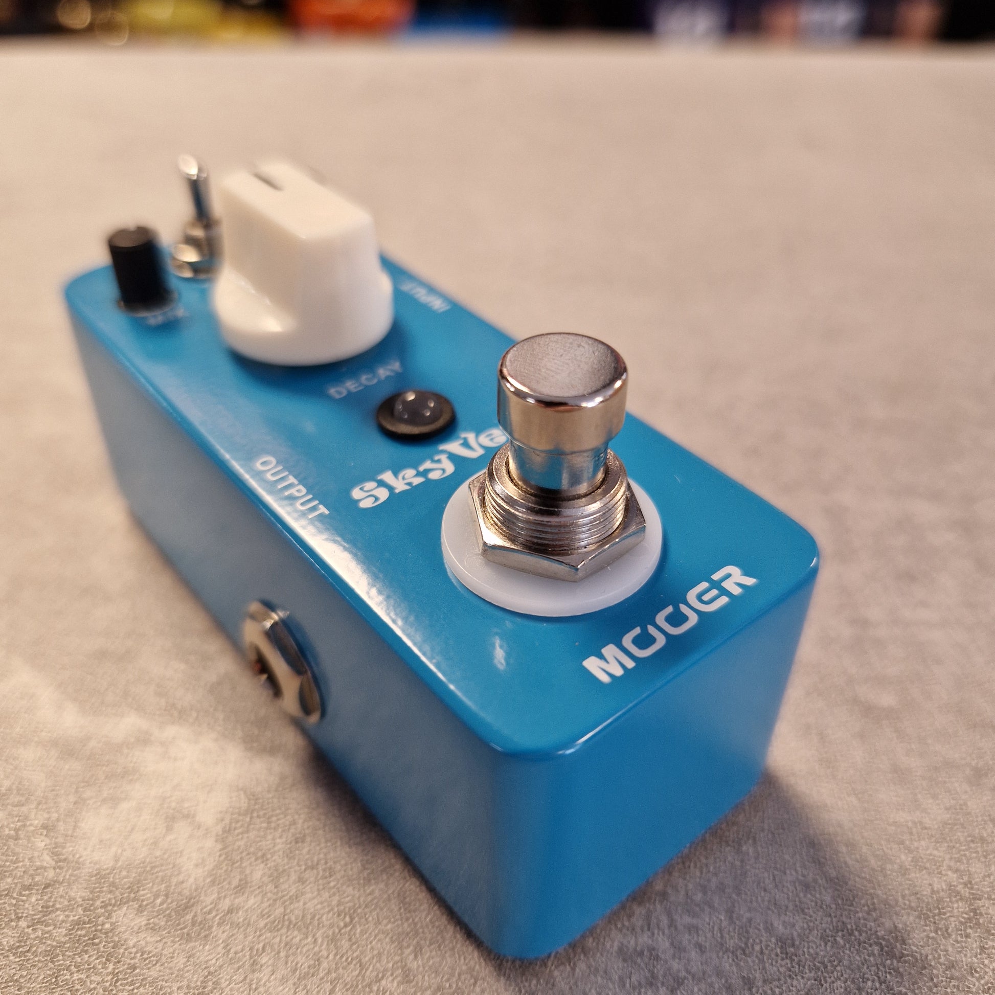 Pre-Owned Mooer MRV2 Blue guitar effects pedal with a switch and output jack on a textured surface
