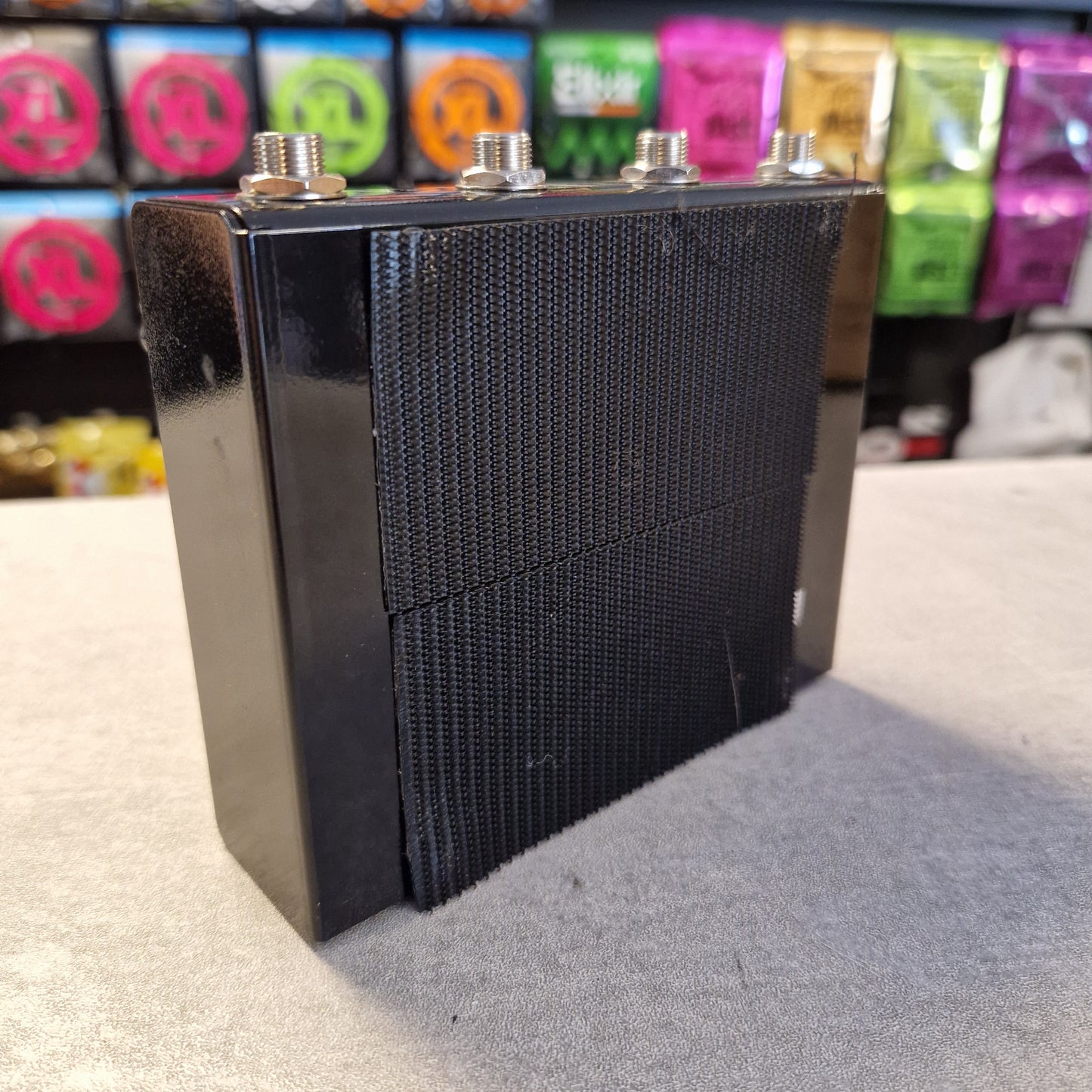 Pre-Owned Truetone VSXO Black speaker grill on a stand with colorful objects in the background
