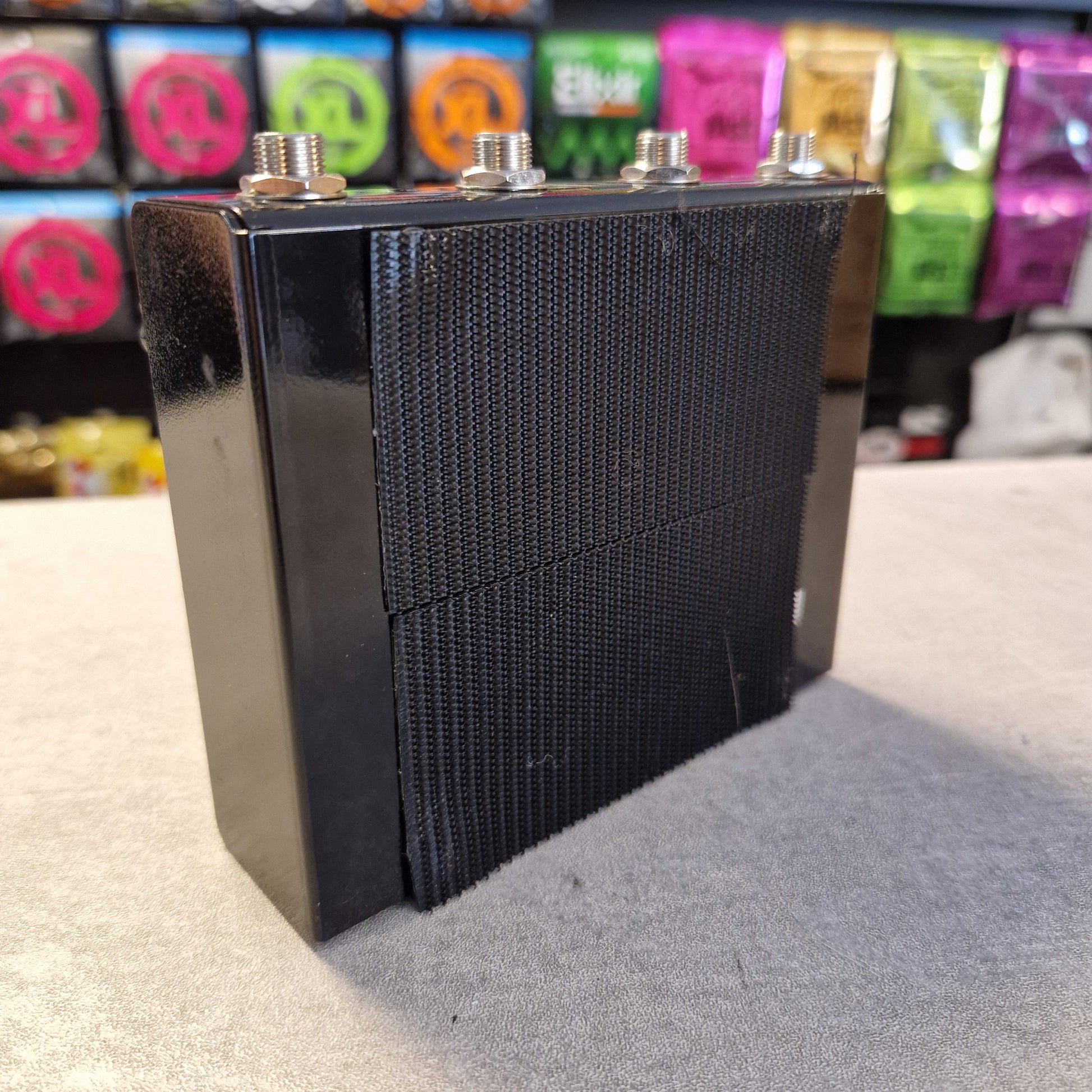 Pre-Owned Truetone VSXO Black speaker grill on a stand with colorful objects in the background
