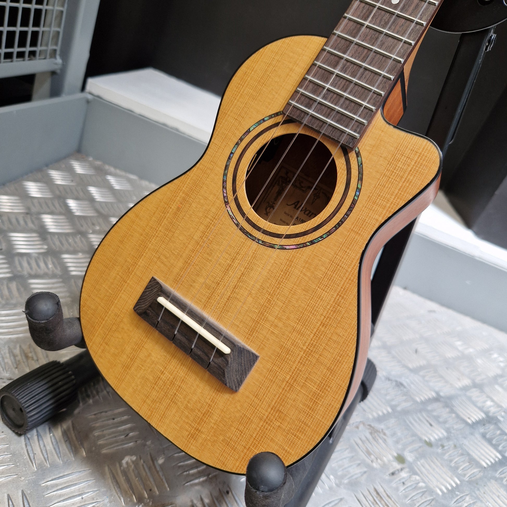 Pre-Owned Alvarez RU26CCE Small wooden guitar on a stand with a textured wall background