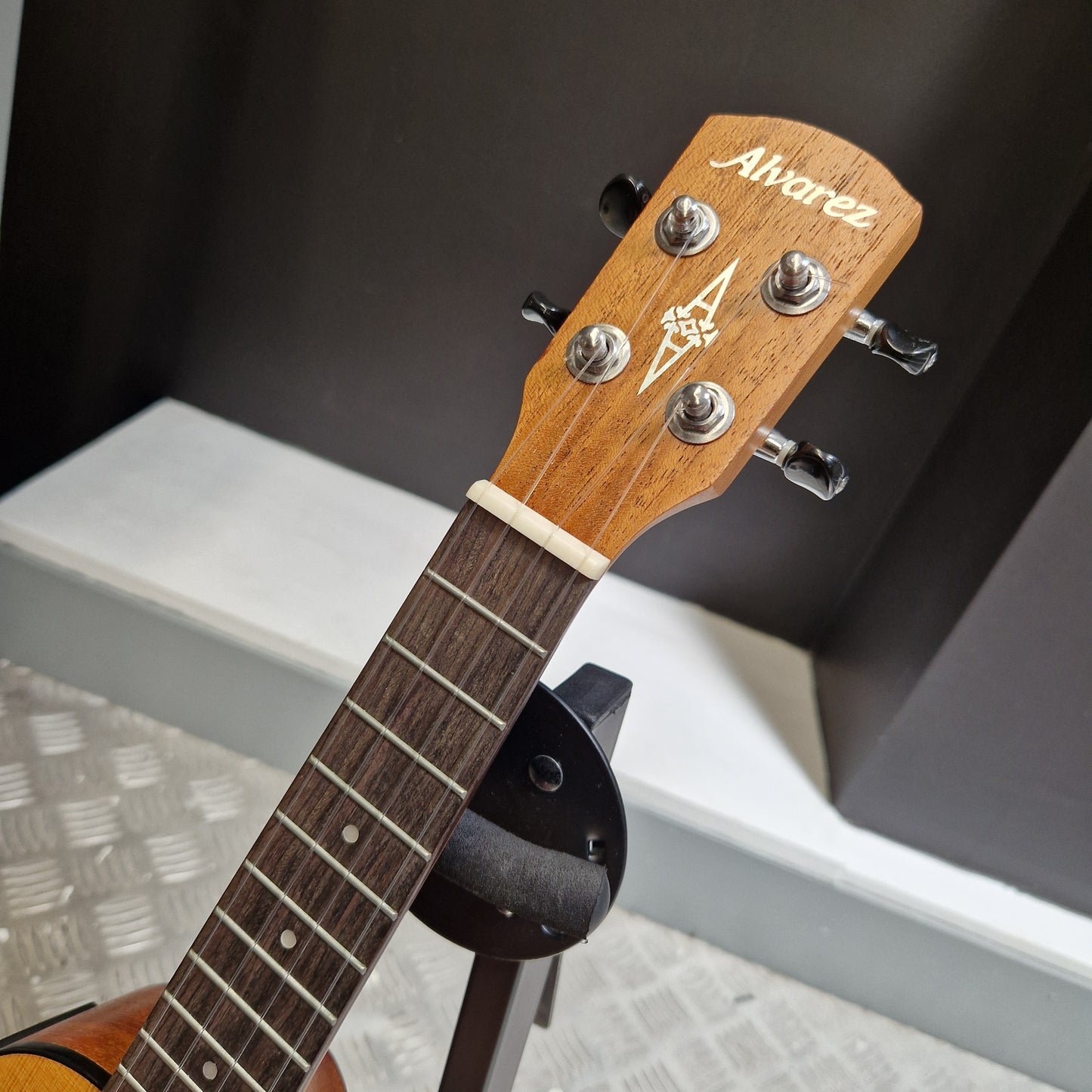 Pre-Owned Alvarez RU26CCE Close-up of a guitar headstock with brand logo against a blurred background