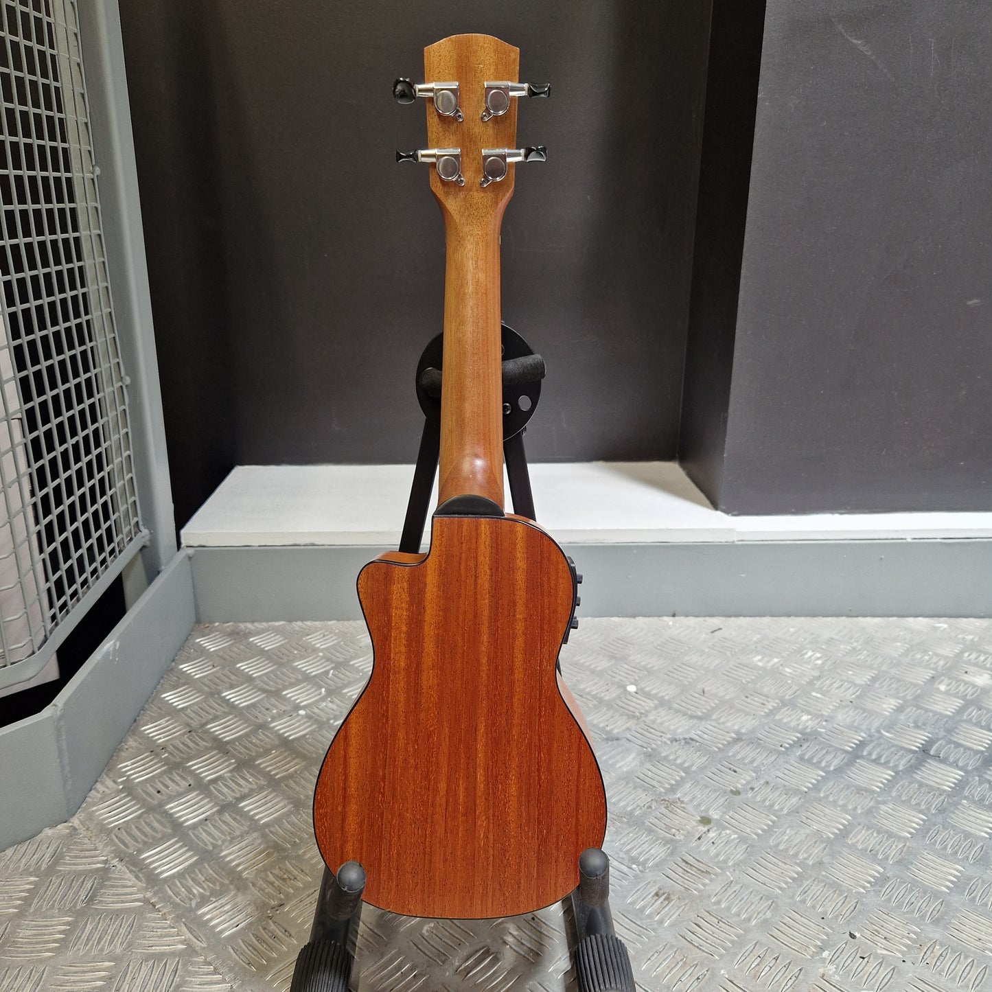Pre-Owned Alvarez RU26CCE Wooden ukulele leaning against a metal wall.