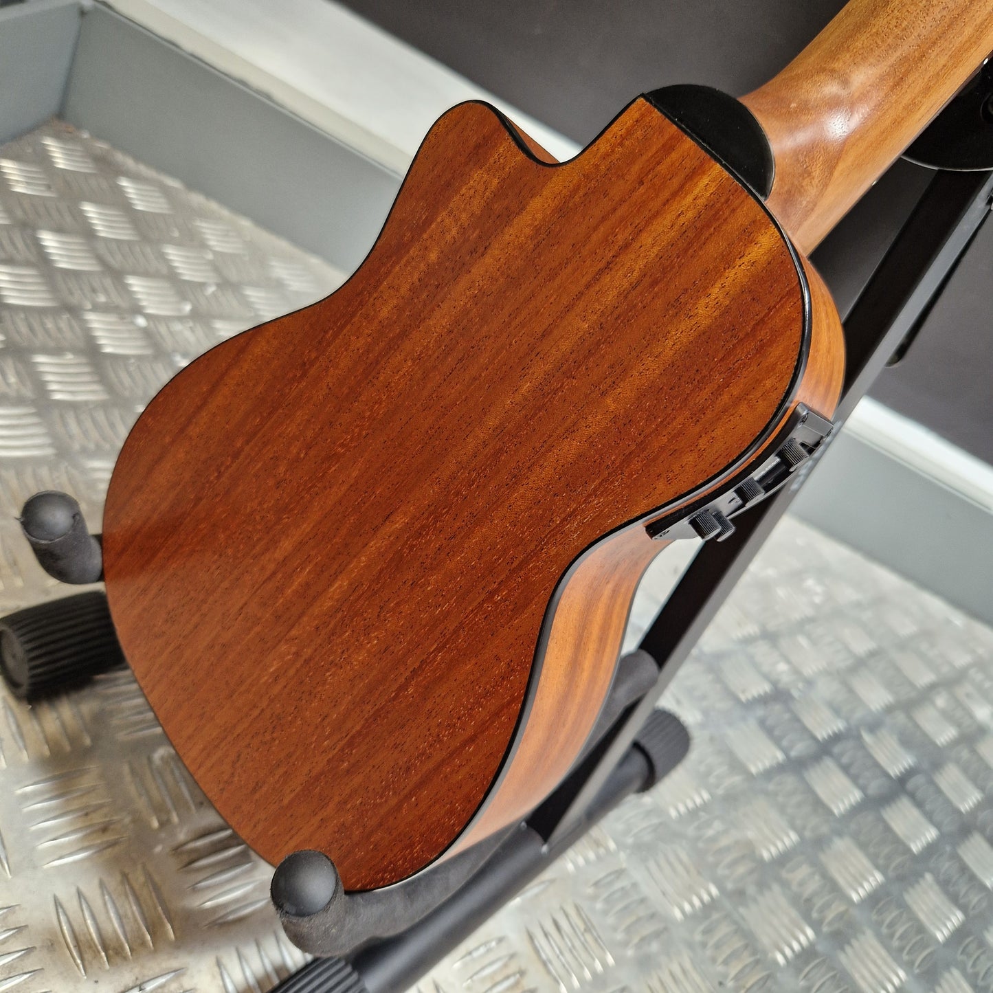 Pre-Owned Alvarez RU26CCE Close-up of a wooden guitar on a stand with a textured wall background