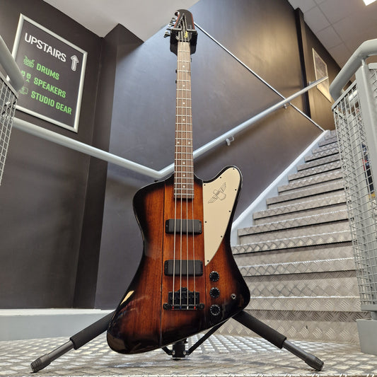 Pre-Owned Epiphone Thunderbird IV Electric guitar on a stand in a music store with a staircase in the background