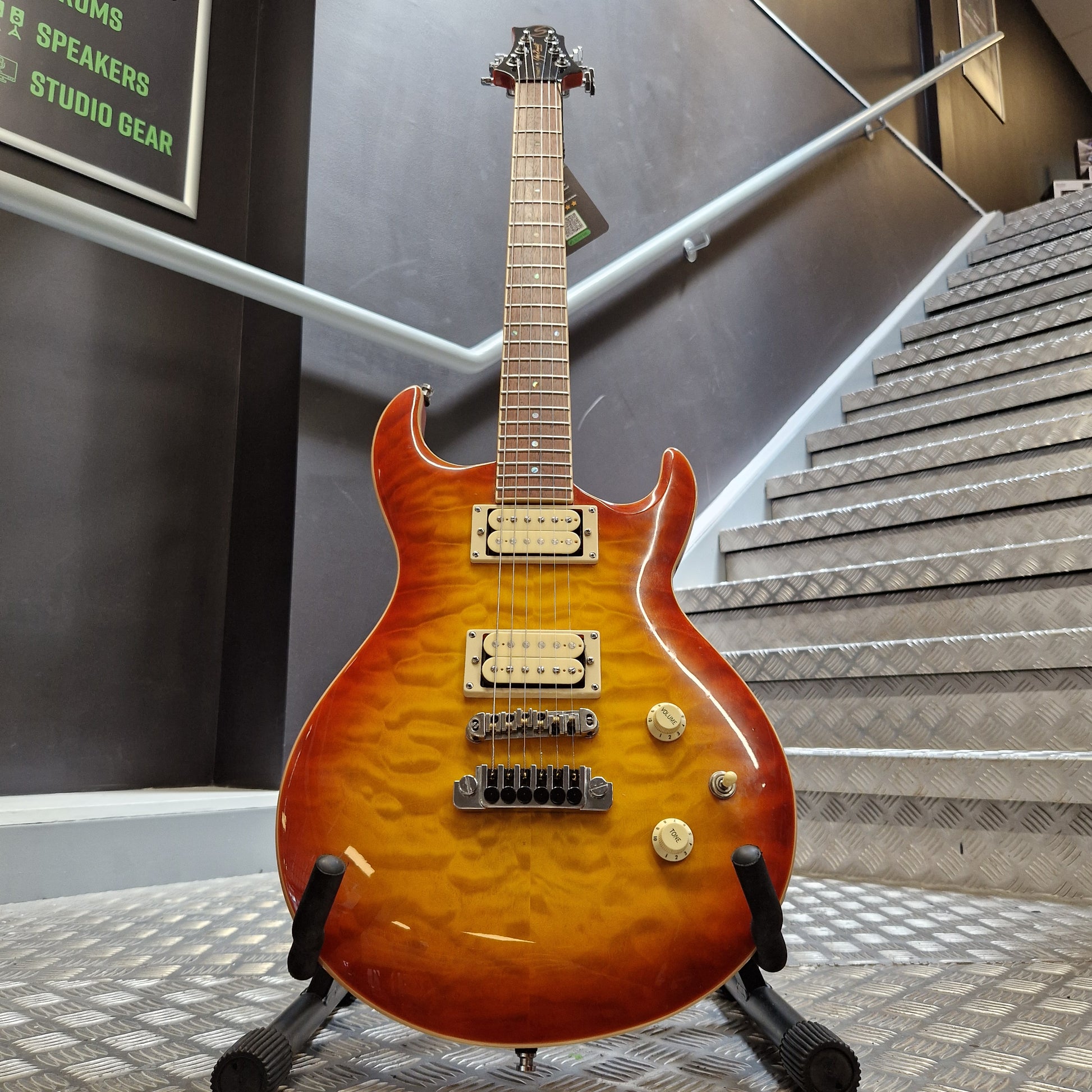 Pre-Owned Samick Orange electric guitar on a stand with a room interior in the background