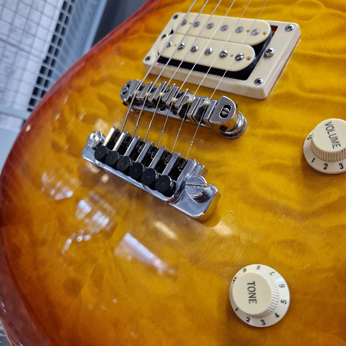 Pre-Owned Samick Close-up of a guitar's bridge and control knobs on a sunburst guitar body.
