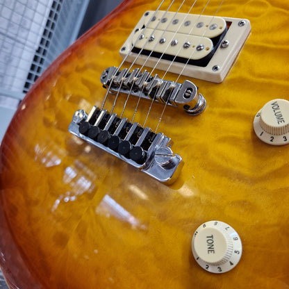Pre-Owned Samick Close-up of a guitar's bridge and control knobs on a sunburst guitar body.