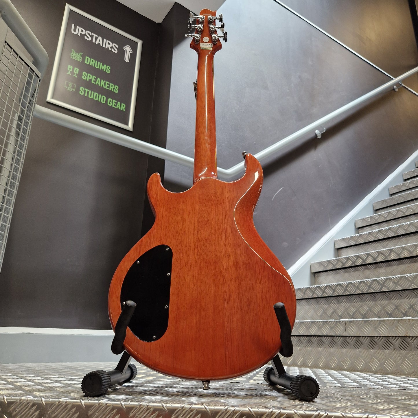 Pre-Owned Samick Electric guitar hanging on a wall with a sign and equipment below