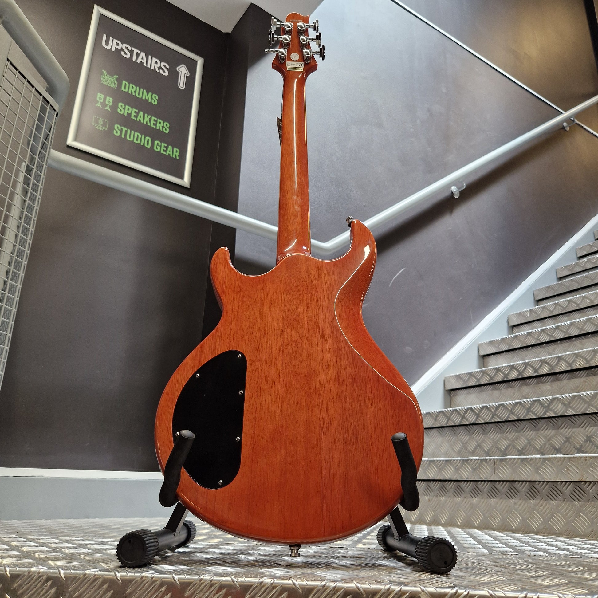 Pre-Owned Samick Electric guitar hanging on a wall with a sign and equipment below