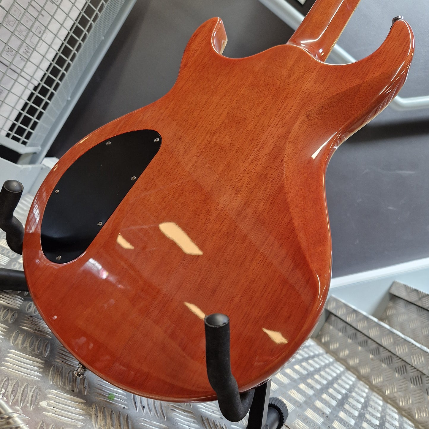 Pre-Owned Samick Close-up of a wooden electric guitar body on a stand.