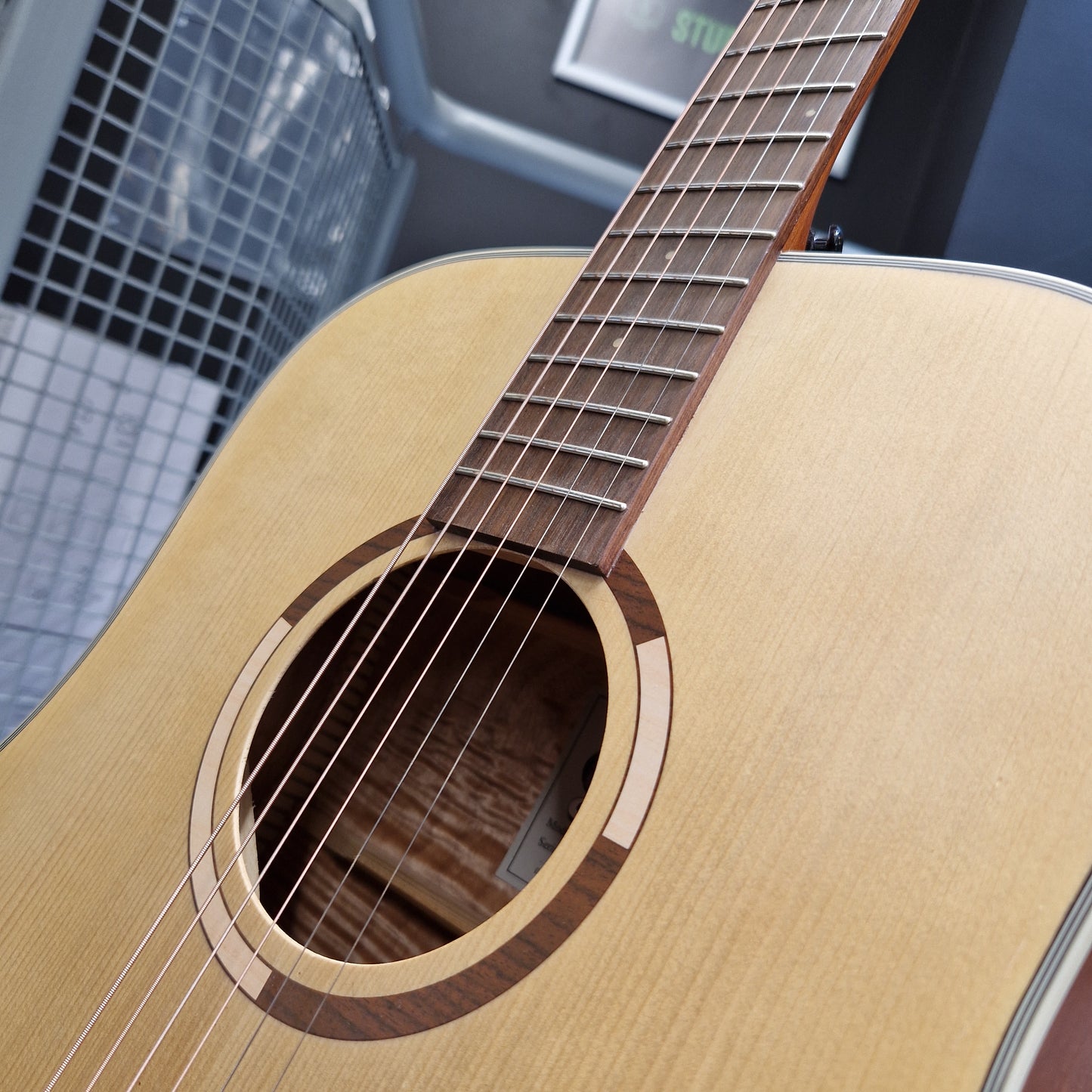 Pre-Owned Tanglewood TS5 Close-up of a wooden acoustic guitar with a blurred background
