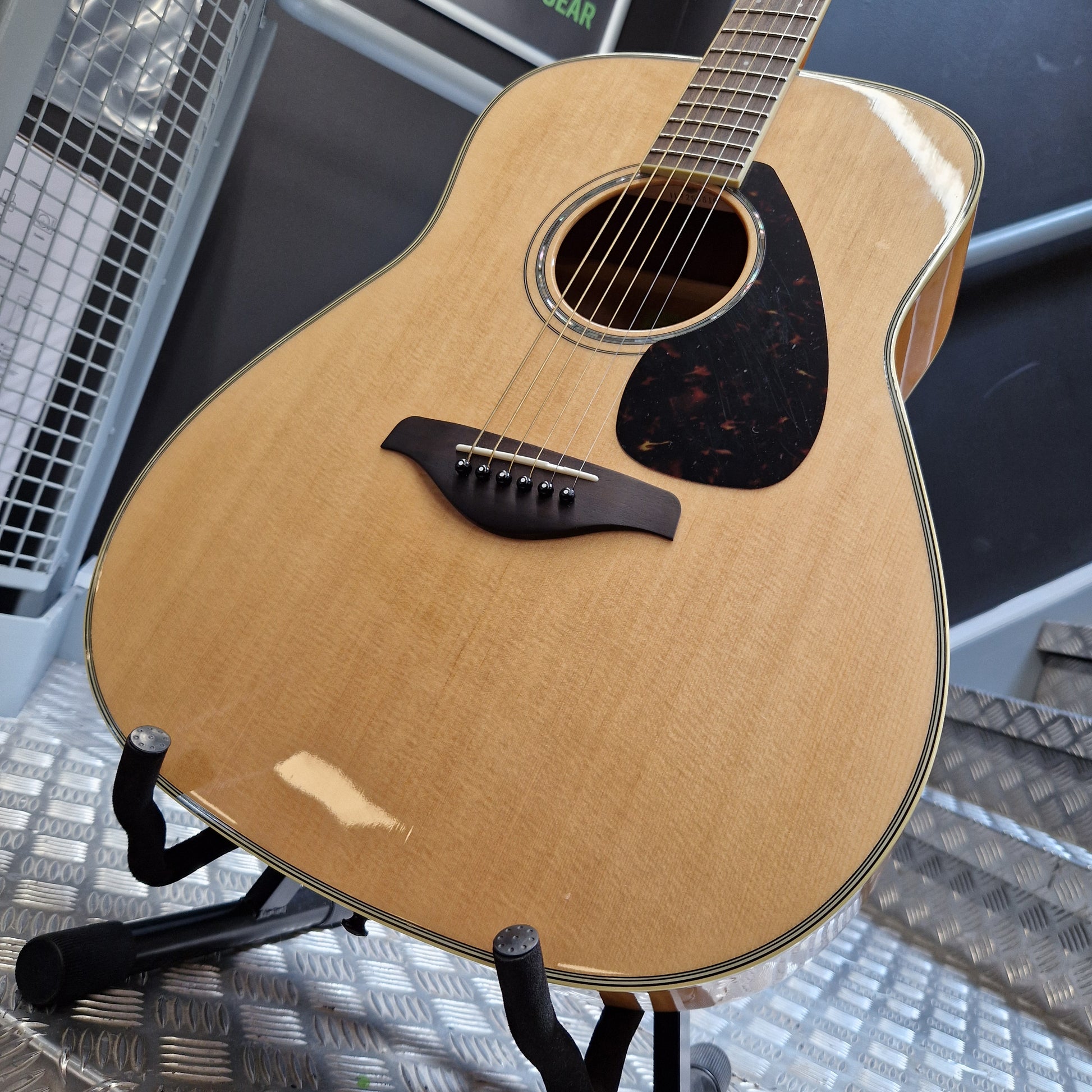 Pre-Owned Yamaha FG840 Acoustic guitar on a stand with a textured surface in the background