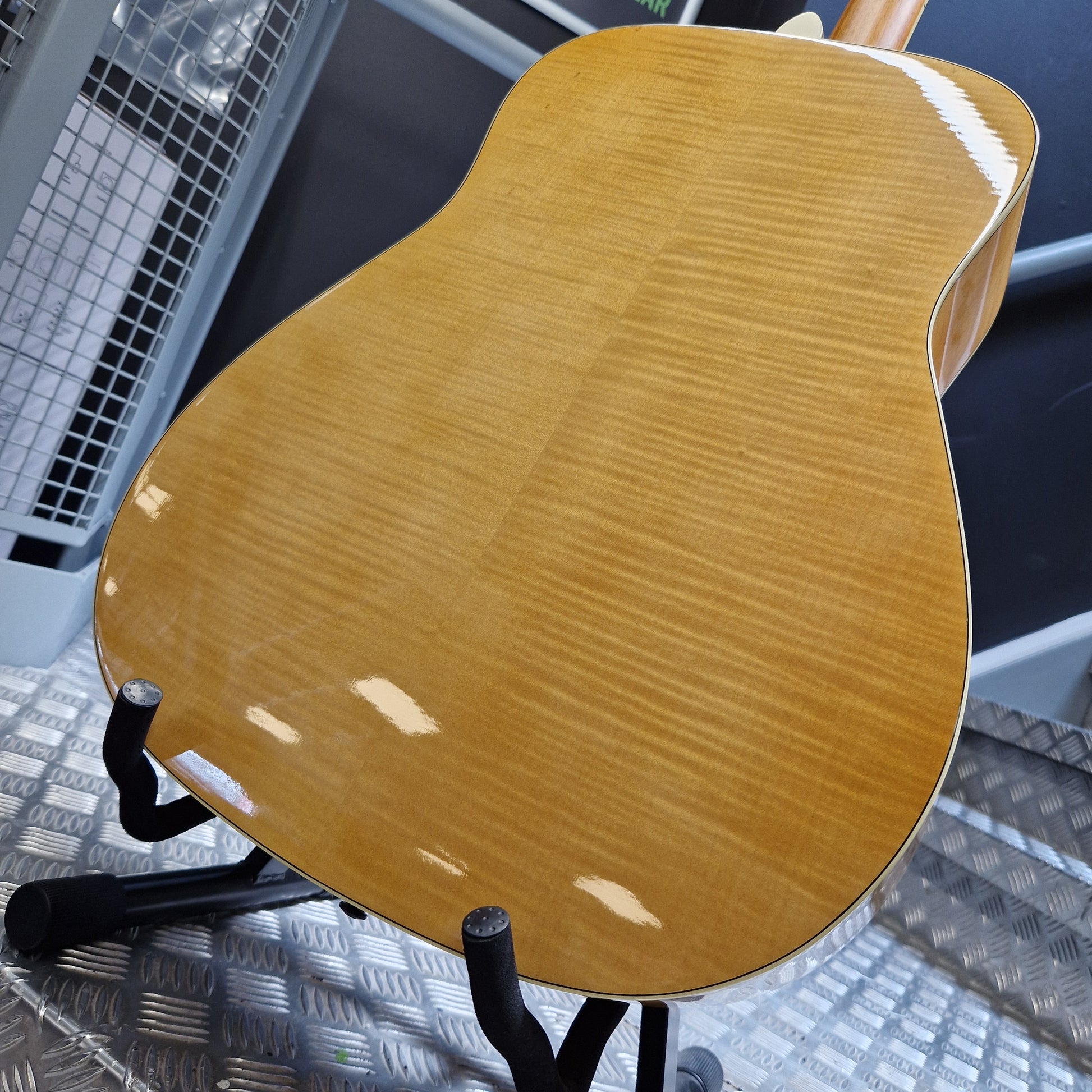 Pre-Owned Yamaha FG840 Close-up of a wooden guitar on a stand with a textured floor background